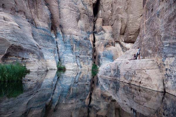 The cool waters are sheltered by sandstone cliffs.